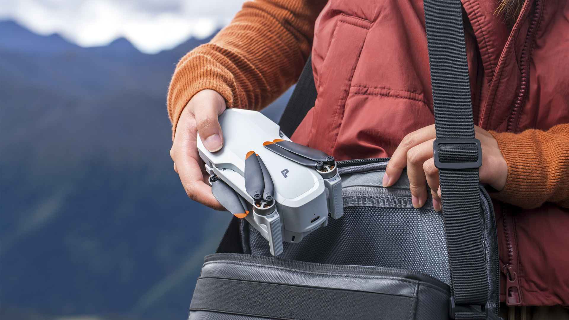 Potensic Atom 2 drone folded, coming out of satchel, mountain backdrop