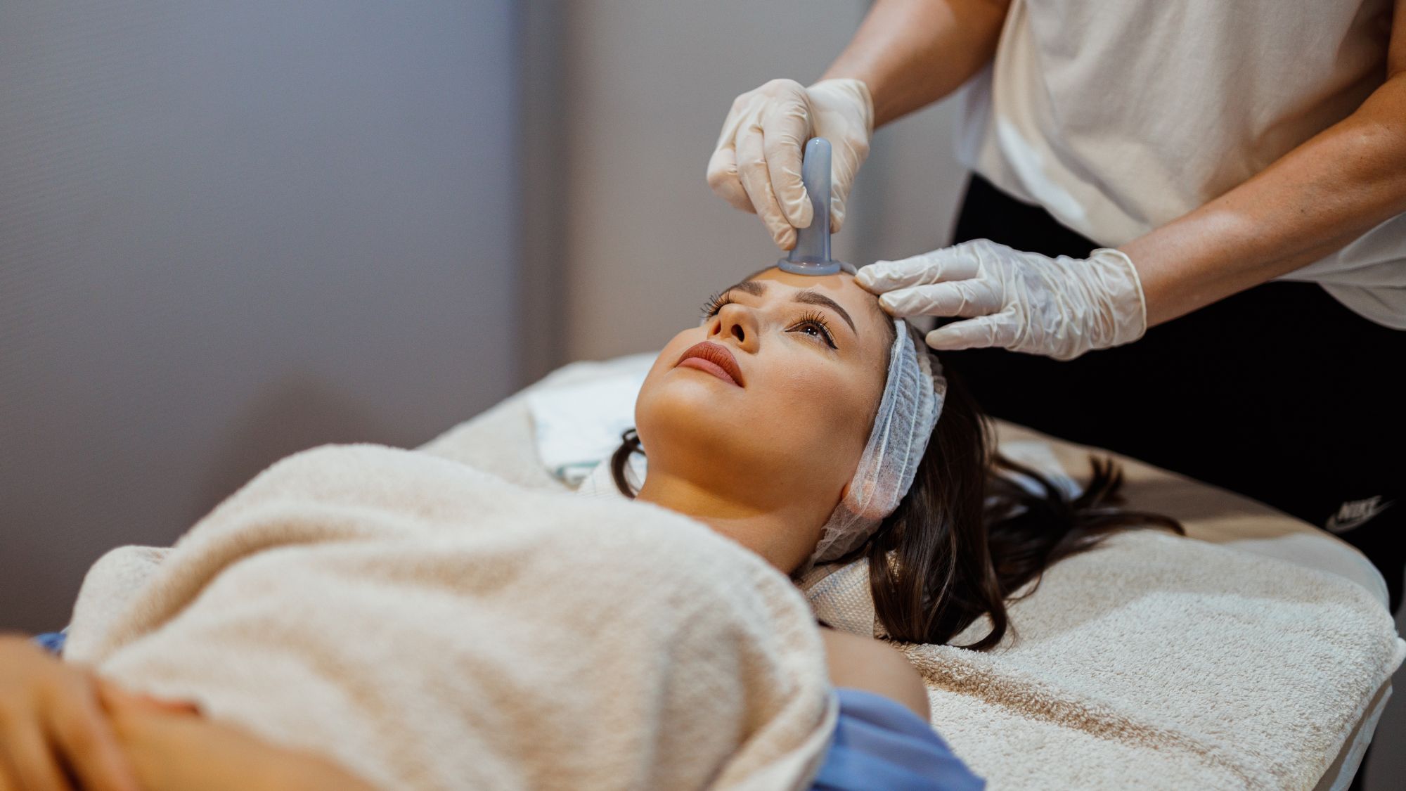 Woman on a treatment table having a facial cupping treatment