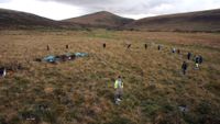 A wide angle shot of a circle of stones in the English moorland with people scattered around