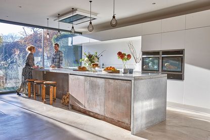 industrial kitchen diner with large metallic island and cage pendant lights