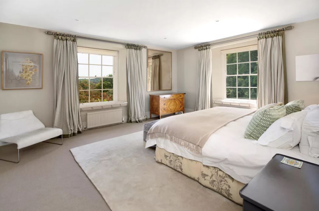 A bedroom in the home with large double bed, large windows and rug on the floor