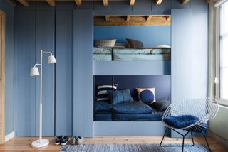 Shared bedroom idea with integrated bunks in painted blue wood in an all-blue scheme.
