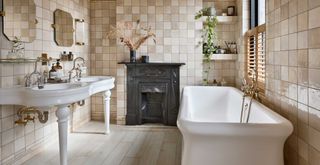 beige tiled bathroom with duble sink and white freestanding curved bath to show a key color bathroom trend 2023
