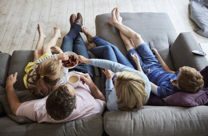 An aerial shot of a family of five sitting together on the sofa to watch TV - How to save money on Netflix