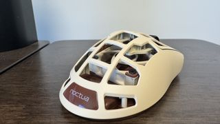 The Pulsar Feinmann F01 Noctua Edition gaming mouse on a wooden desk, from the back right showing off the Noctua logo