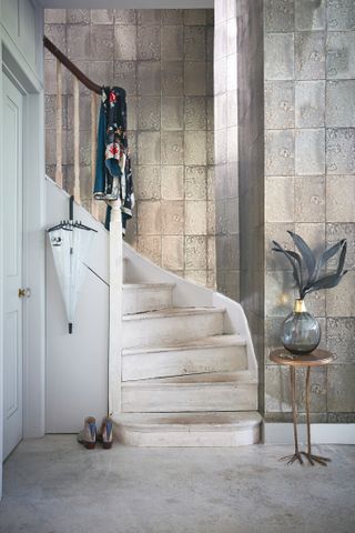 Hallway with metallic wallpaper and white washed stairs