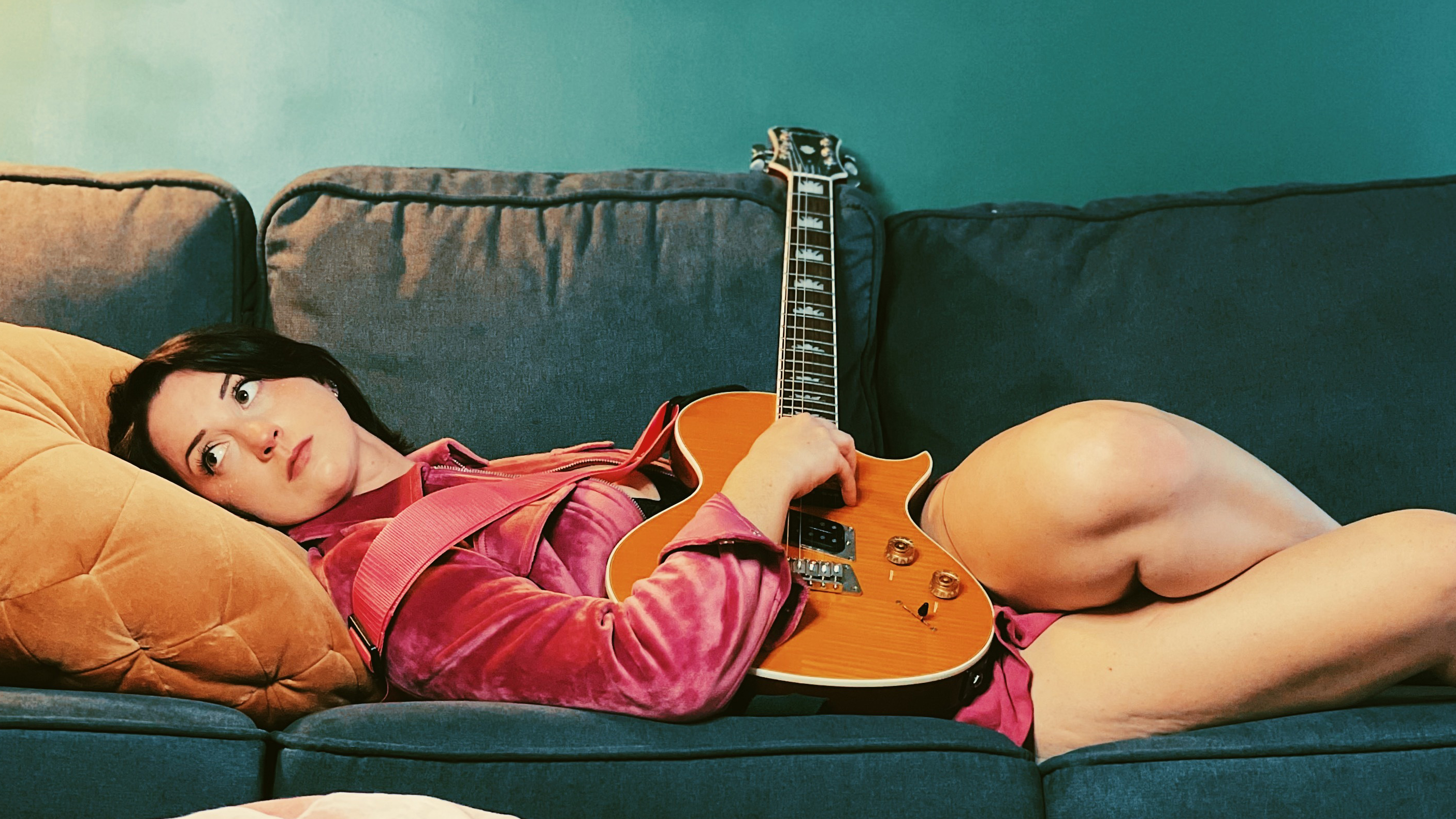 Foxanne/Gohd, on a couch with her guitar