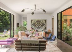 a living room with patterned wall hanging and open patio doors to the outside