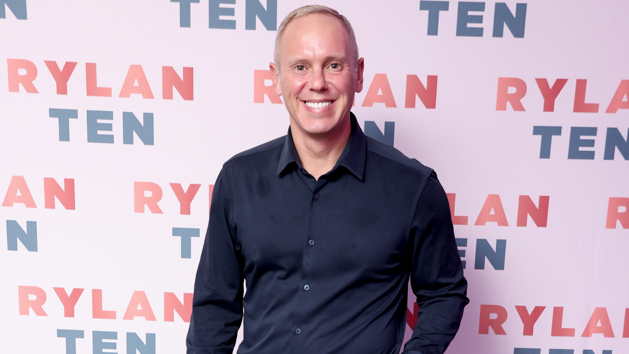 Rob Rinder wears a navy shirt to a press event