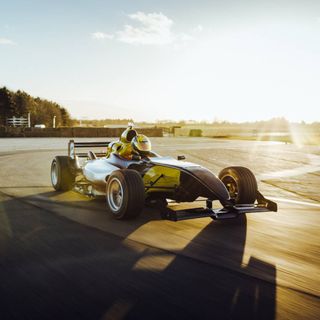 A man sits in a Formula One racing car on a sunny day