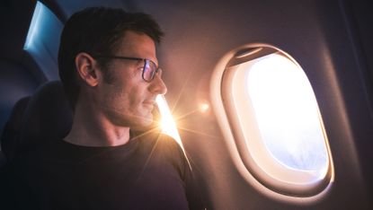A man looks out the window on an airplane.