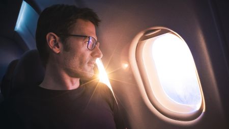 A man looks out the window on an airplane.