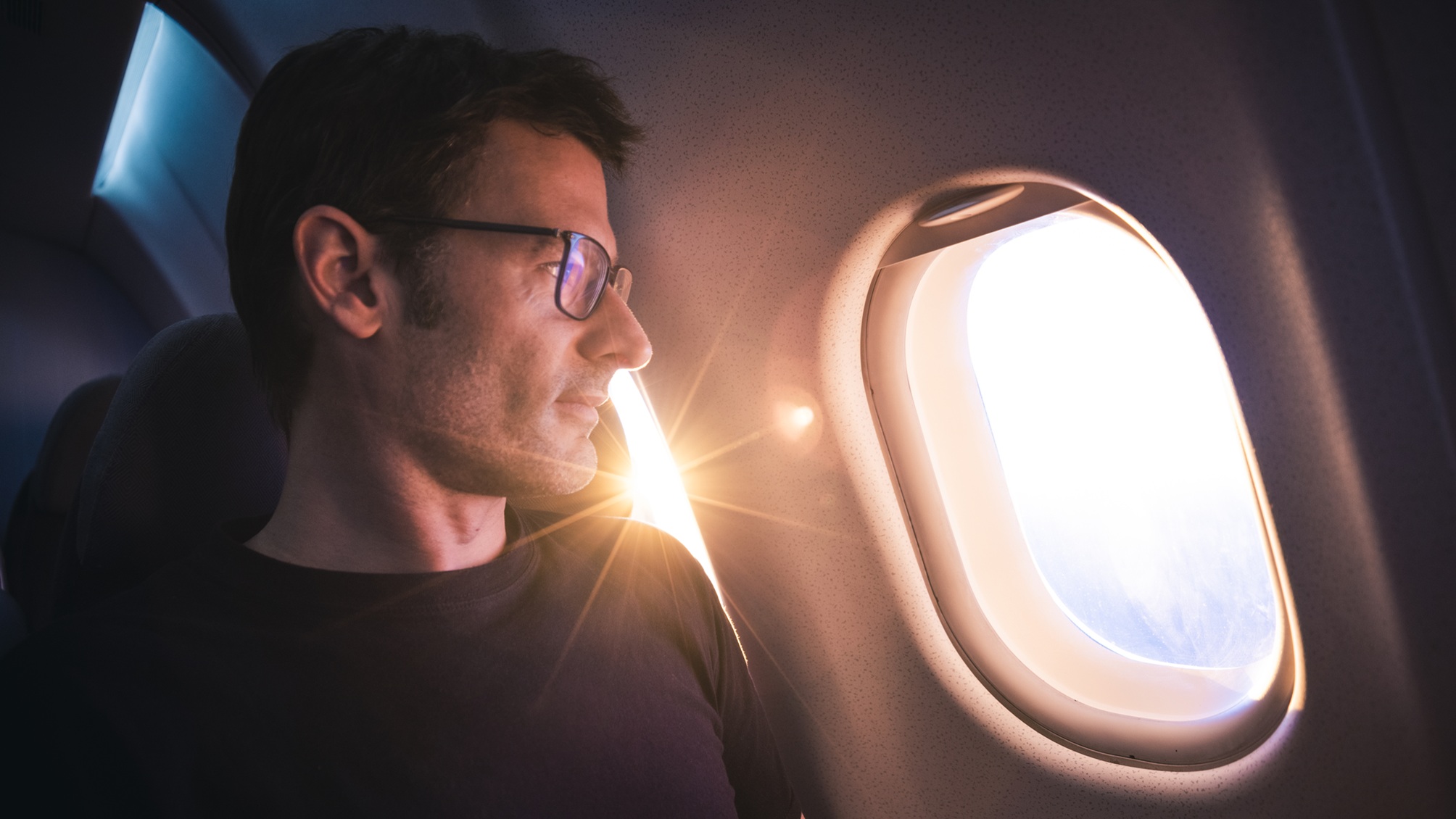 A man looks out the window on an airplane.