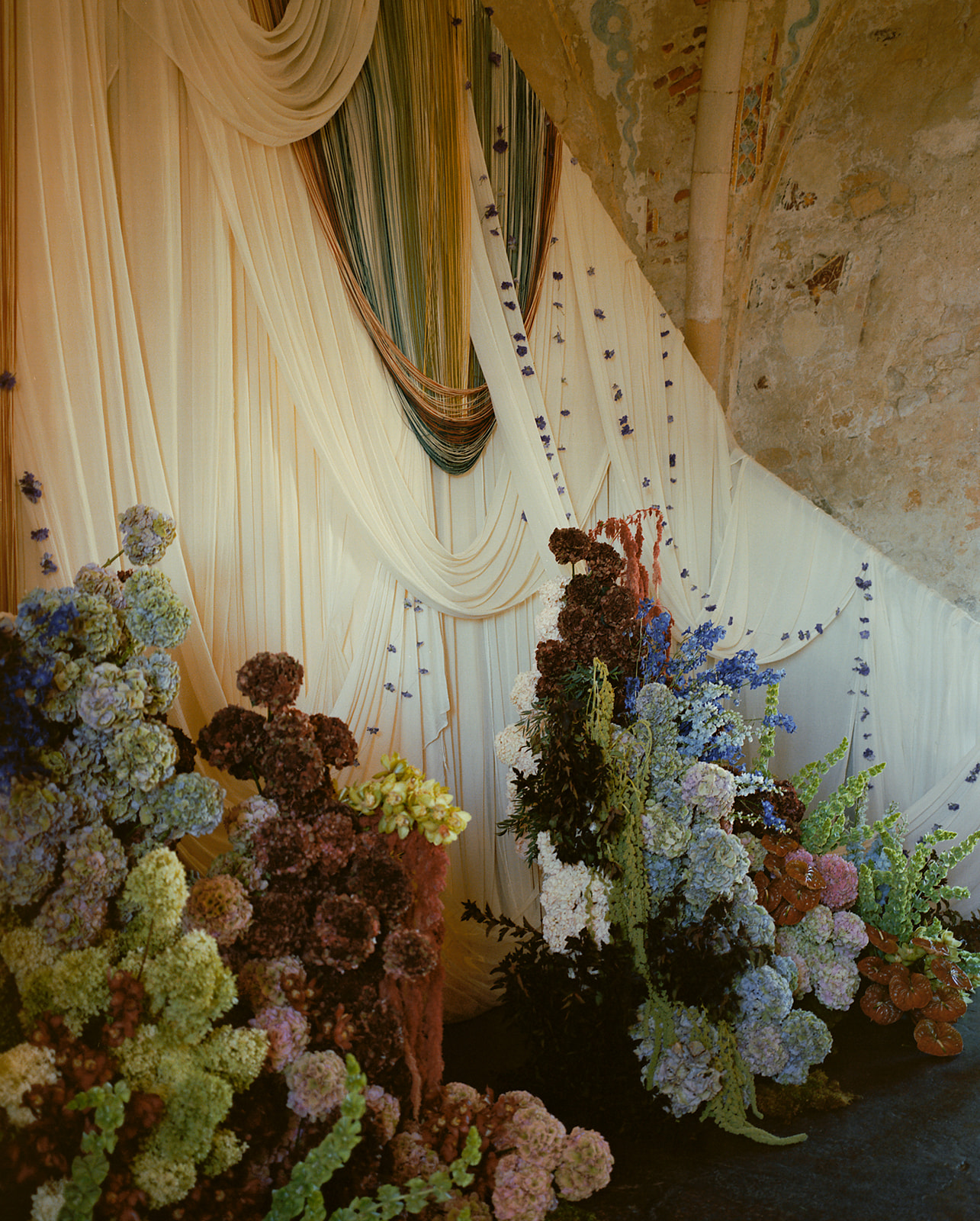 A textile and colorful floral installations set inside a rock church.
