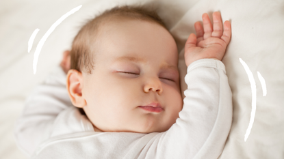 A sleeping baby dressed in white with arms over its head