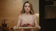 Kaitlyn Dever holding a plate of fruit in Apple Cider Vinegar