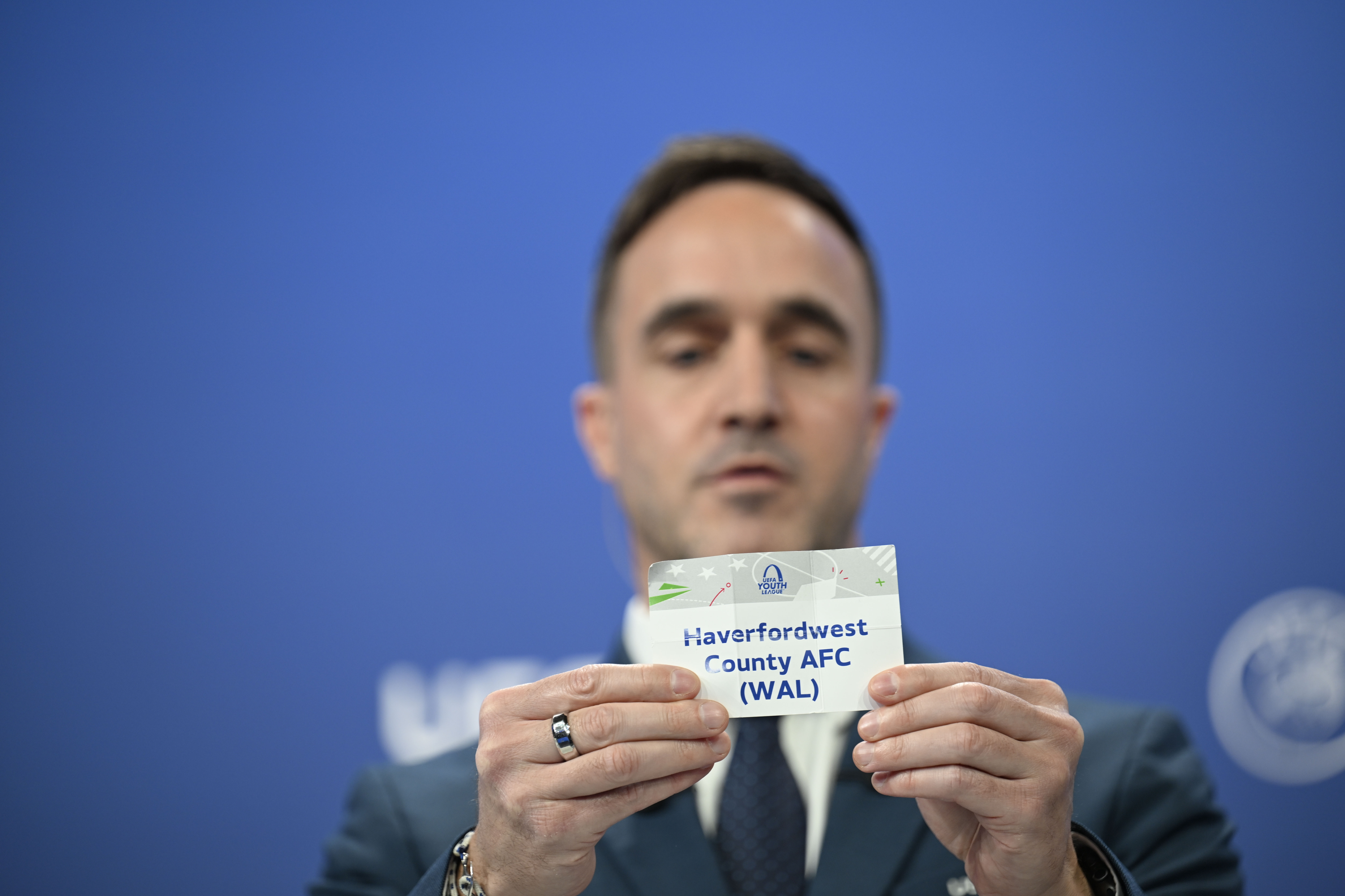 NYON, SWITZERLAND - SEPTEMBER 1: UEFA Head of Club Competitions Management Tom Barlow draws out the card of Haverfordwest County AFC during the UEFA Youth League 2025/26 Domestic Champions Path Round 1, 2 And 3 Draw, at the UEFA Headquarters, The House of the European Football, on September 1, 2025 in Nyon, Switzerland. (Photo by Kristian Skeie - UEFA/UEFA via Getty Images)