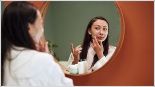 Asian woman applying moisture cream at her face