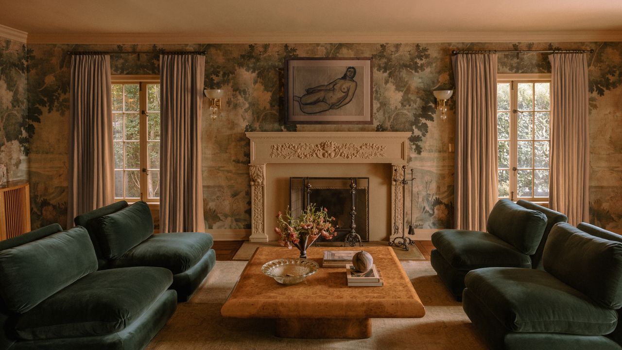 Living room with traditional mural on walls, blue-green velvet sofa, burr wood coffee table