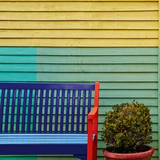 Colourfully painted garden fence and wooden chair in garden area