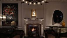 Dimly lit living room featuring a roaring fireplace, wall art, and sculptures.