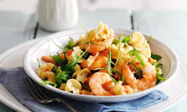 A vibrant bowl of pasta tossed with succulent prawns, red chilies, and burst cherry tomatoes
