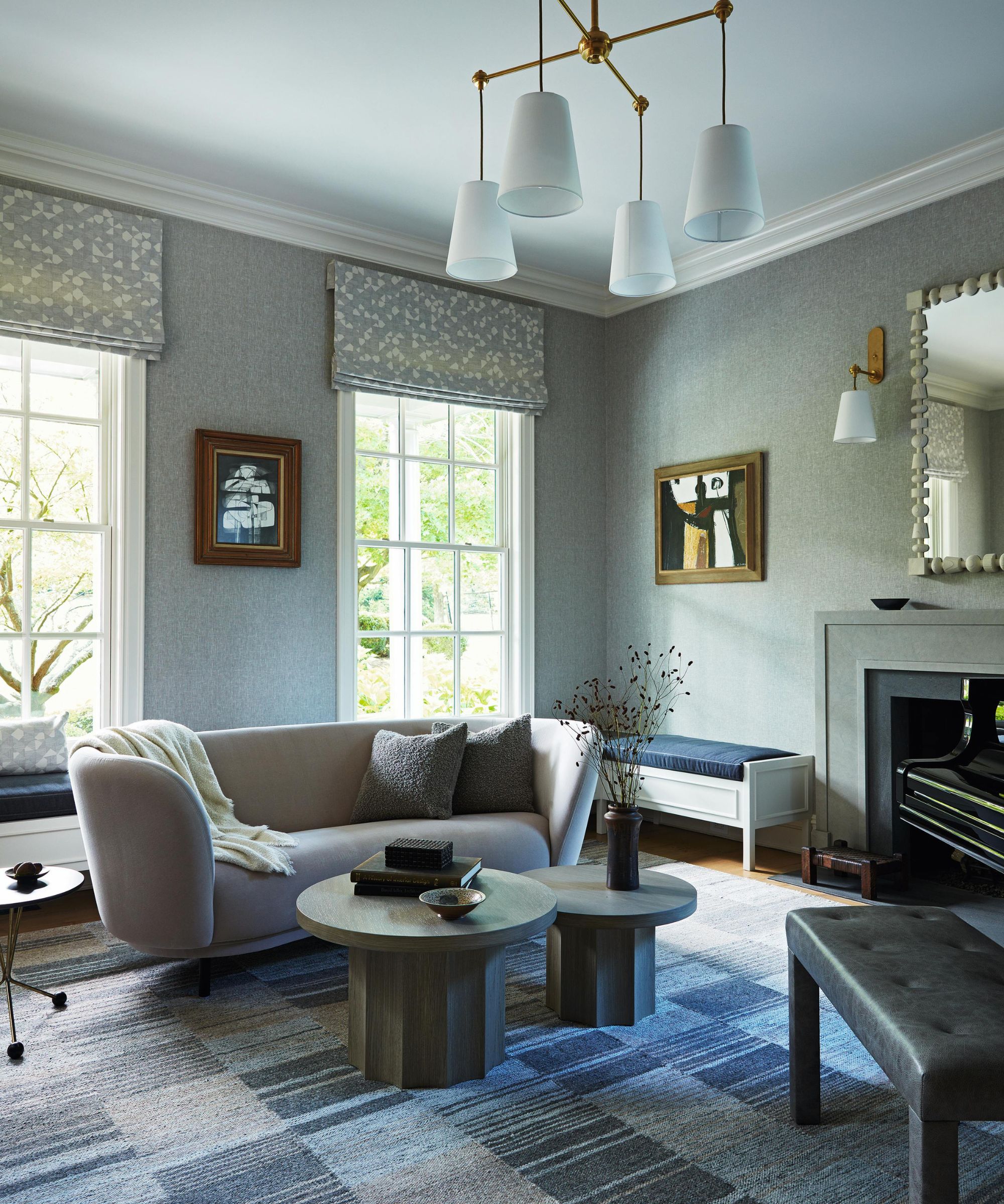a soft blue music room with patchwork rug, fireplace, curved couch and round coffee tables