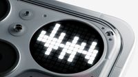 A macro close-up reveals a circular LED pixel display on the back of a device, illuminated with white blocks to form a decorative pattern.