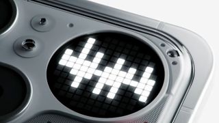 A macro close-up reveals a circular LED pixel display on the back of a device, illuminated with white blocks to form a decorative pattern.