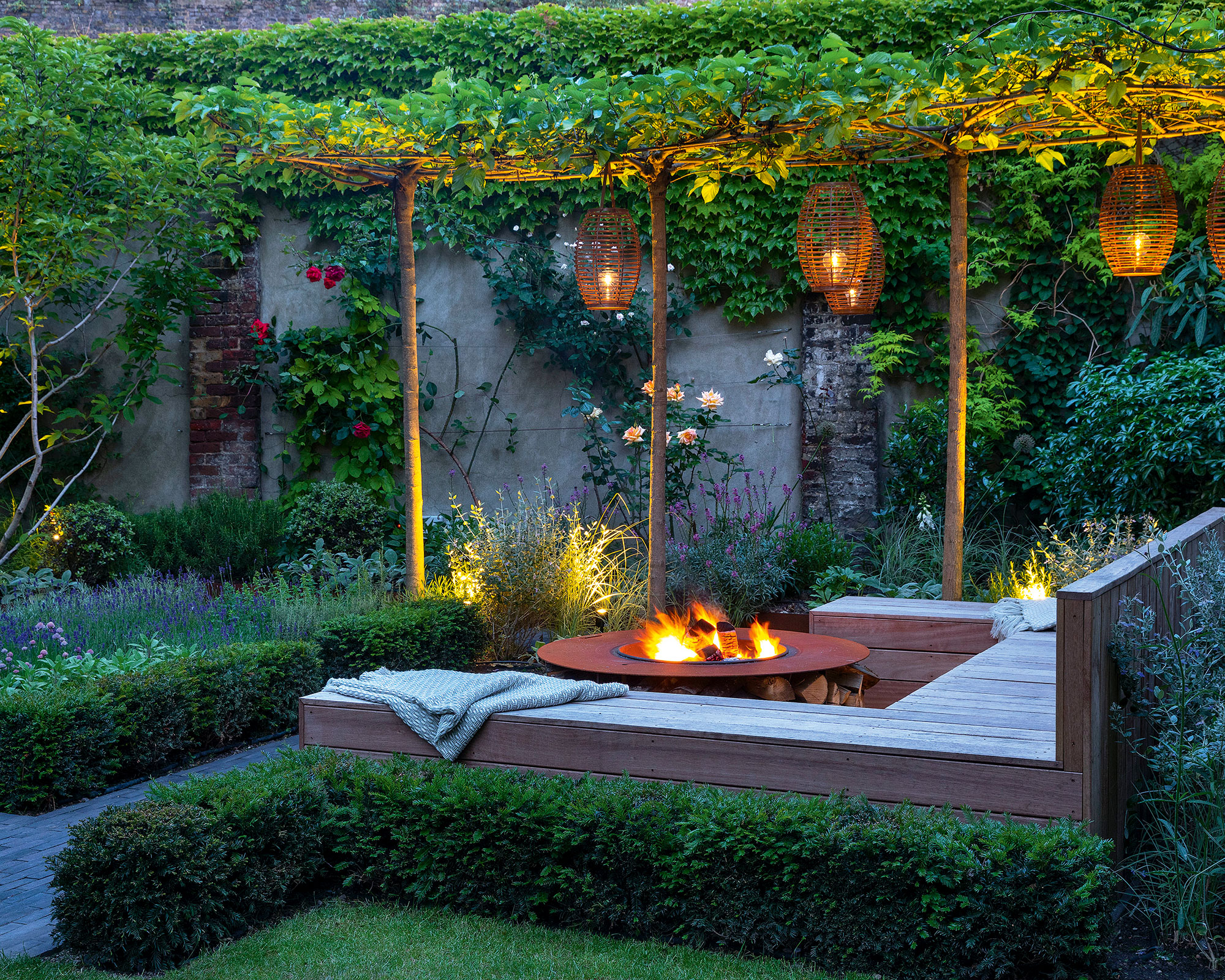 Cozy garden with garden lights and hanging lanterns and firepit