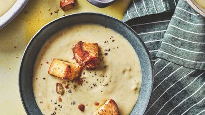 A bowl of potato and leek soup with garlic croutons