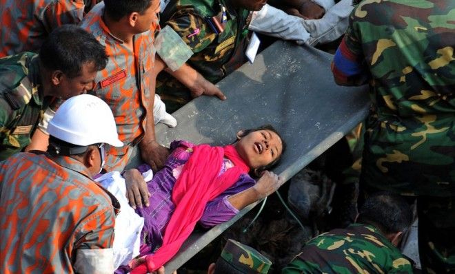 Rescuers carry a woman who survived under the rubble by eating biscuits from the bags of dead colleagues. 