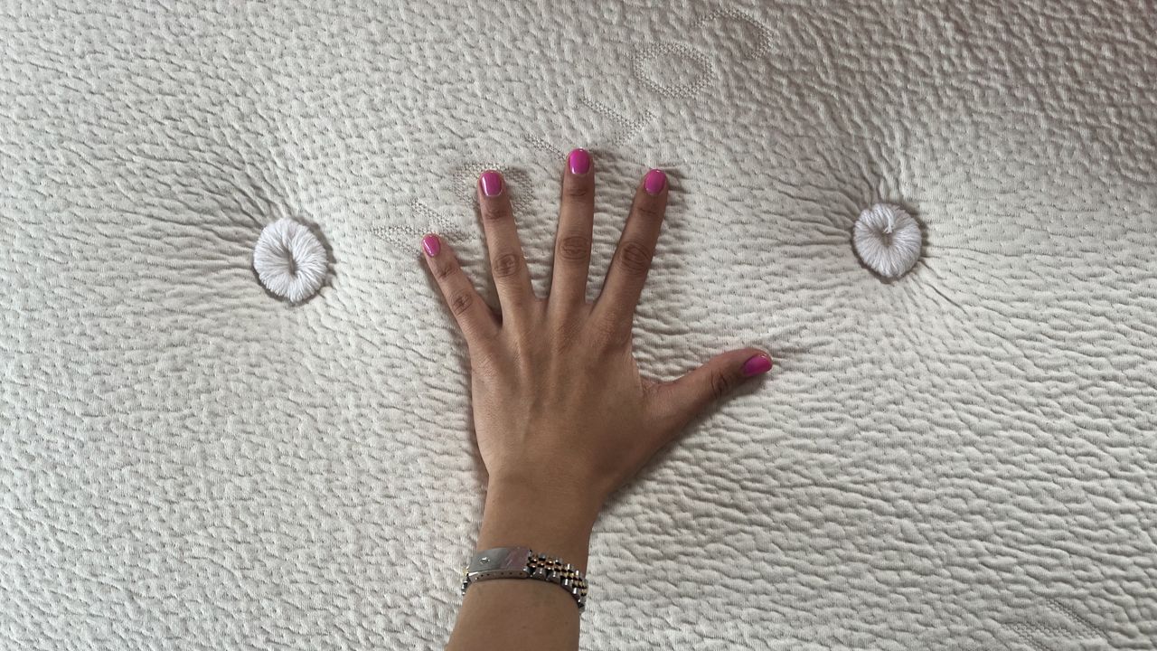 A woman's hand with pink nails pressing into the cool to the touch Avocado Green Mattress