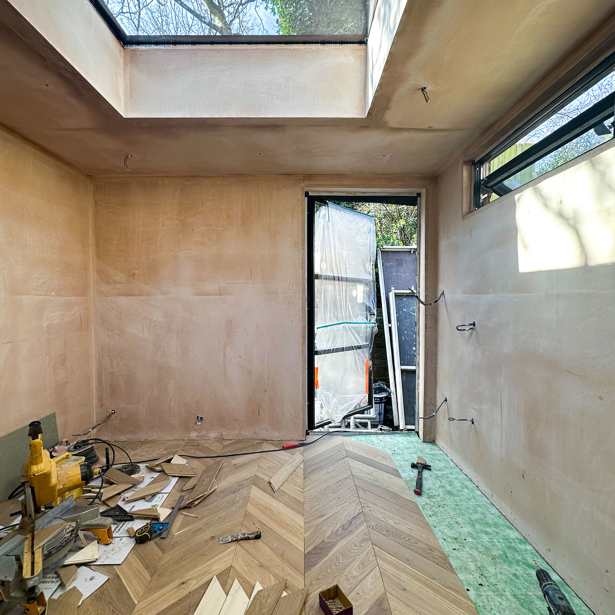 Interior of newly built space with wooden flooring, bare surfaces and skylight