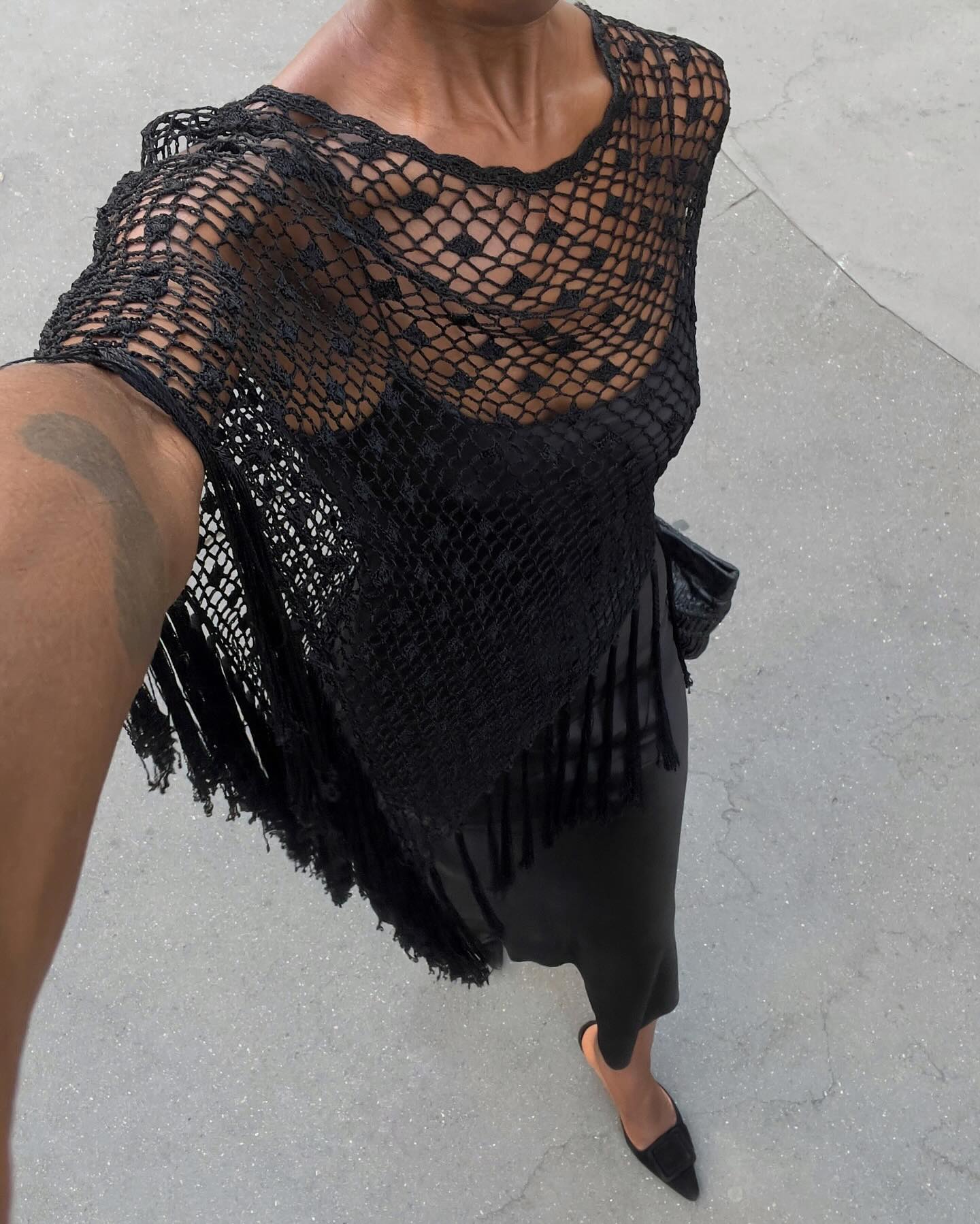 Sylvie Mus wears a black tassel poncho and black heels