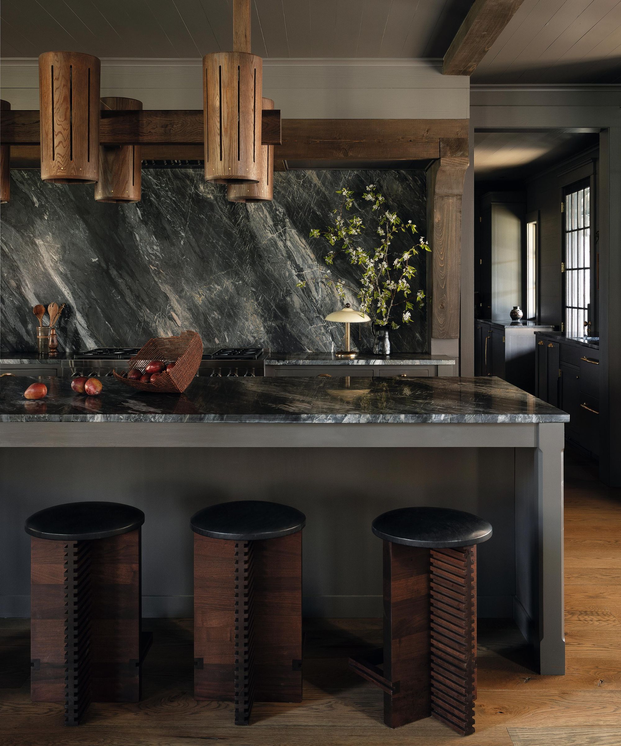 a moody dark grey farmhouse kitchen with statement marble stone and rustic wooden beams