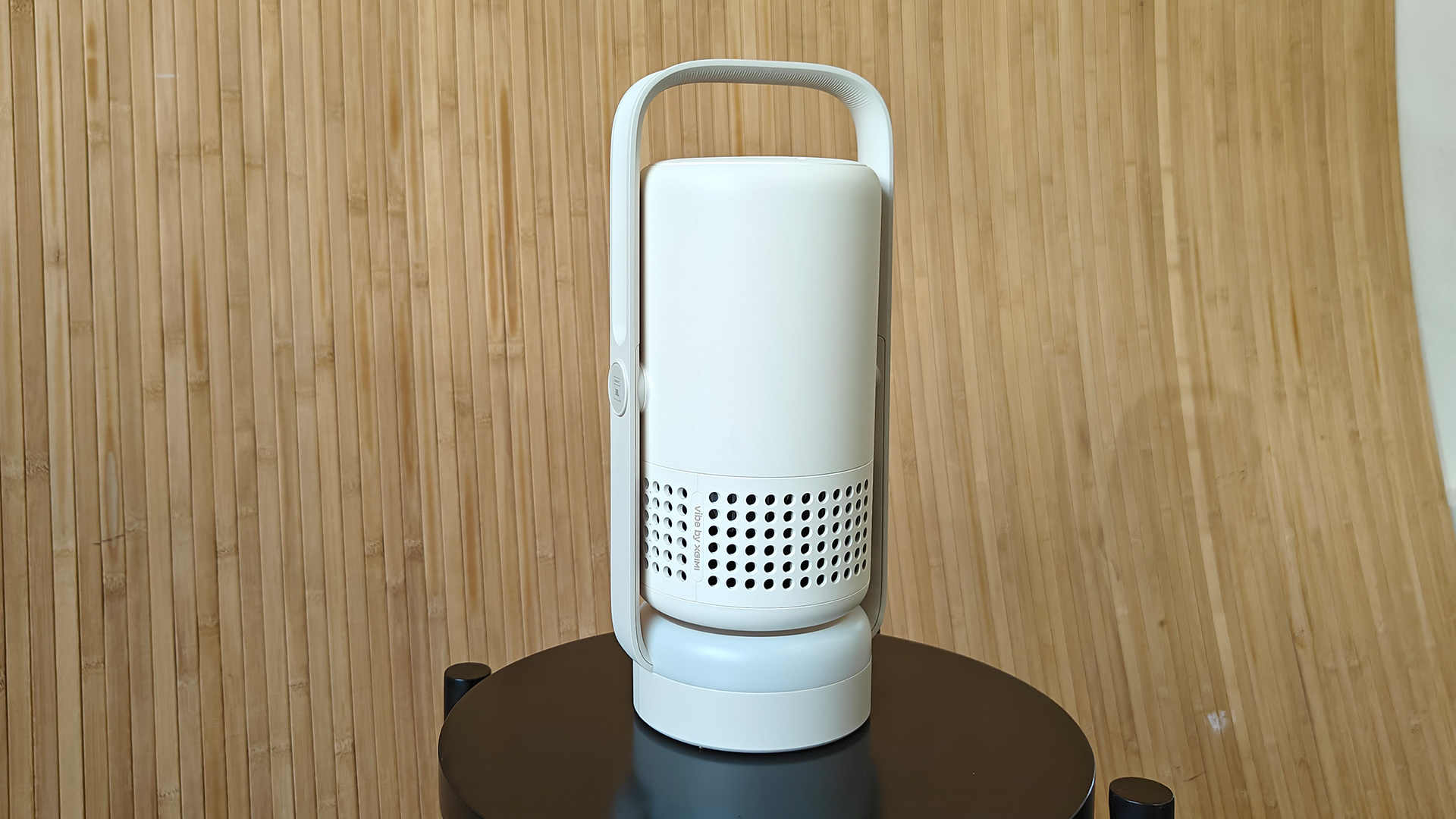 Xgimi Vibe One portable projector on its end on small black table in Bluetooth speaker mode