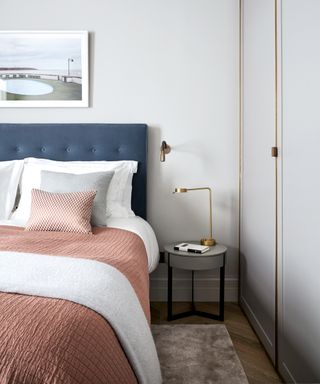 A white bedroom idea with blue velvet headboard and pink bedding