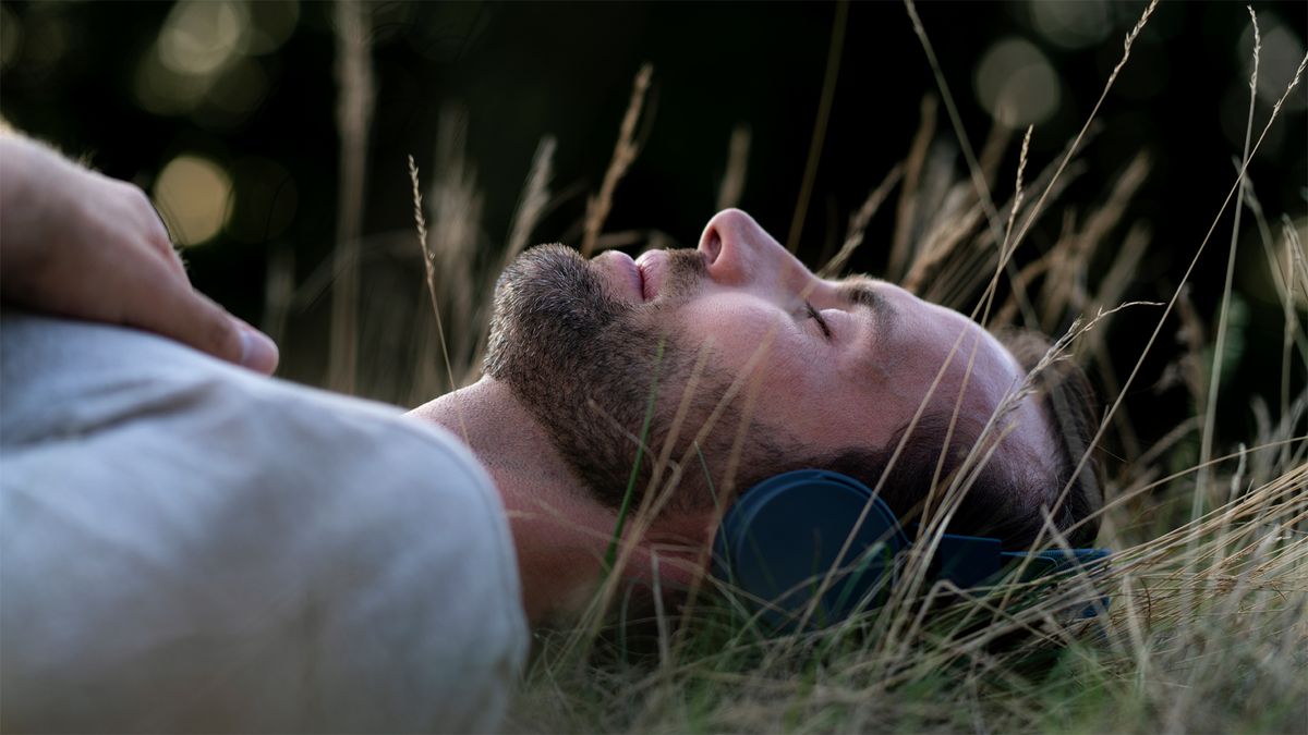 A man listening to headphones in the grass