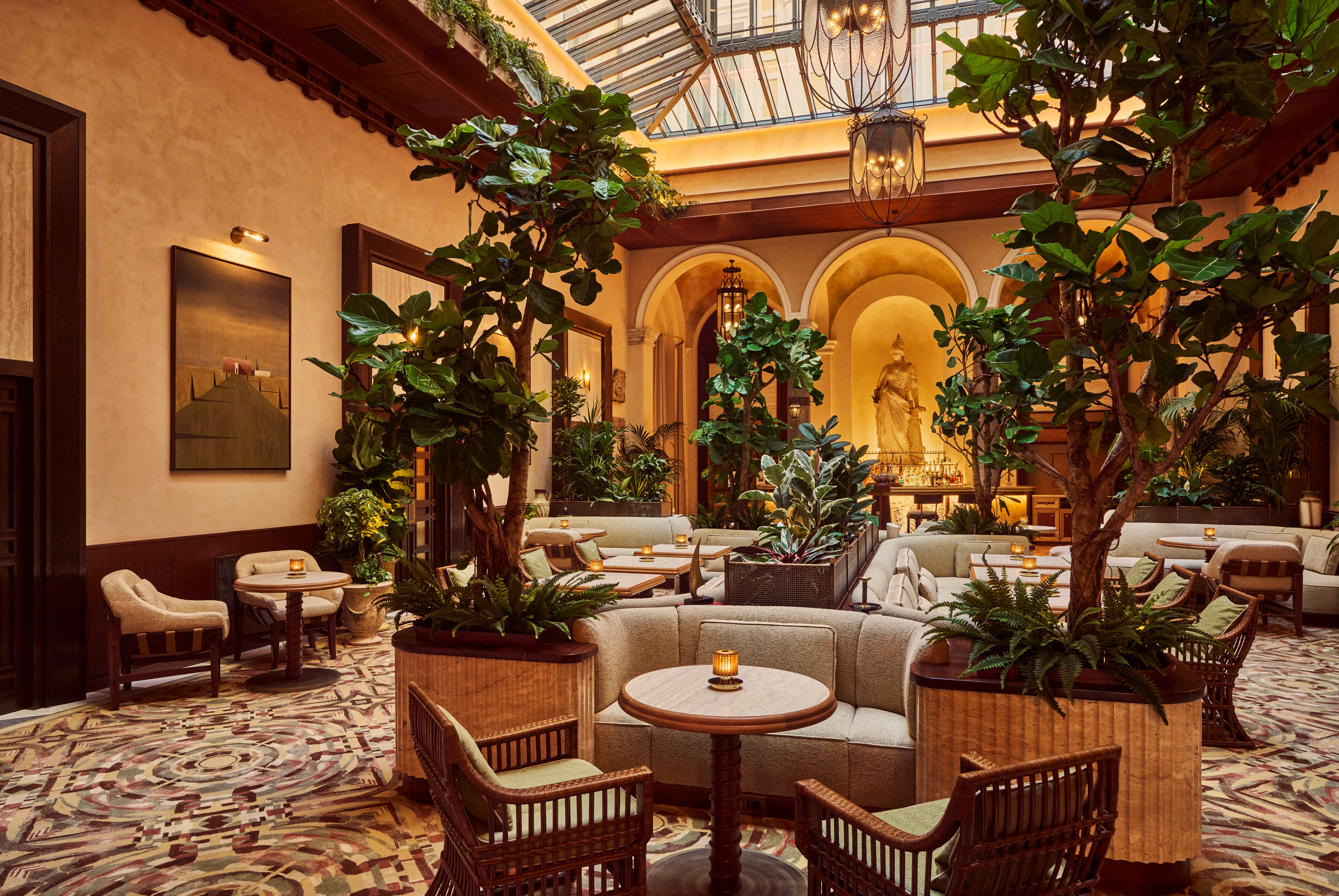 The interiors of a palatial hotel housed inside a 16th-century building with frescoed walls, textural arches, mesmerizing flooring, and plenty of wood oozes antique-inspired furniture and a golden atmosphere across sculptural furnishings, artworks, and plants.