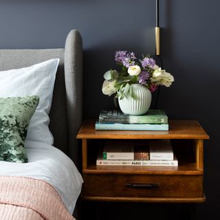 A navy bedroom with a wooden bedside table