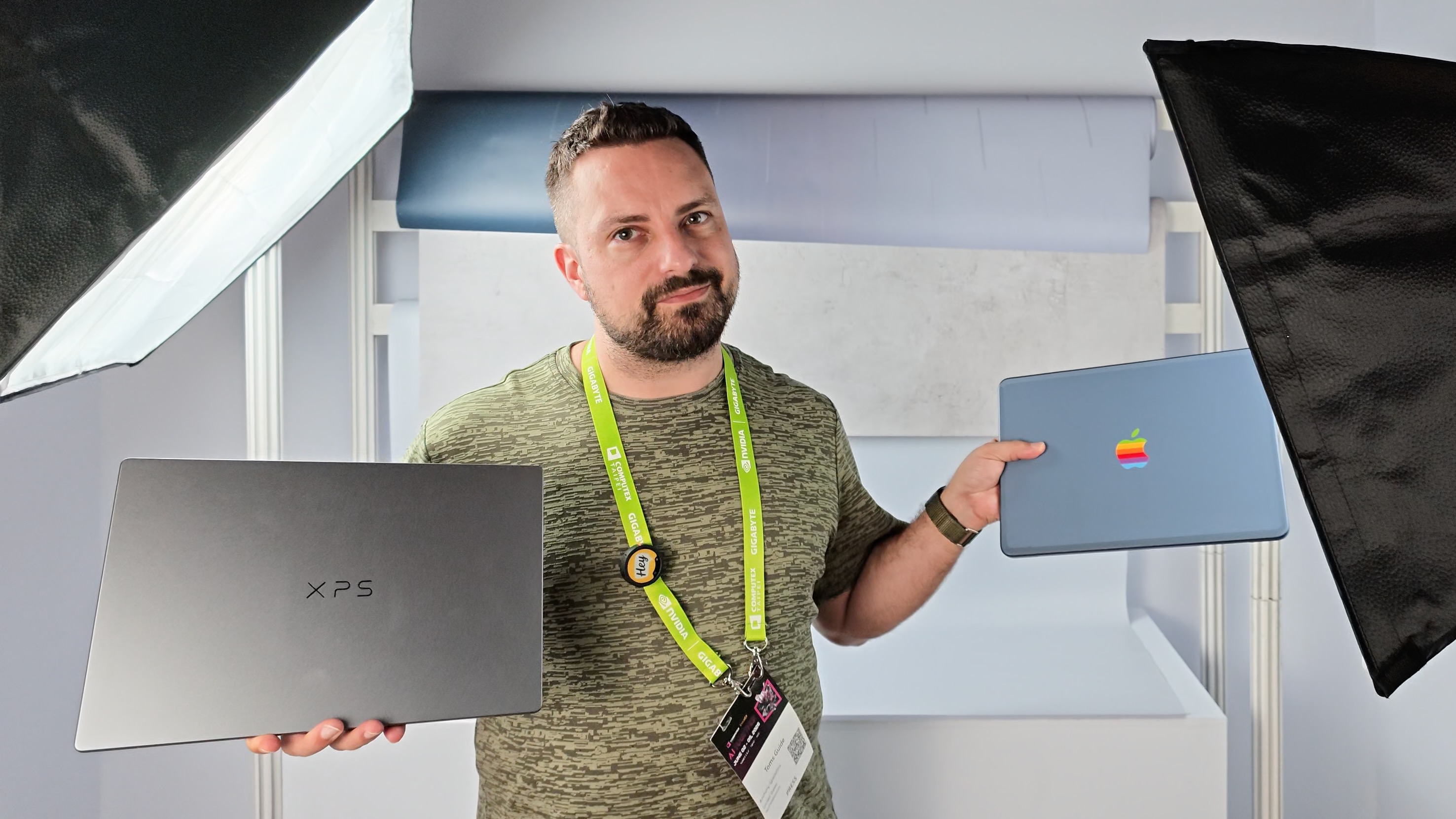 A person holding the Dell XPS 13 (2026) in one hand and the MacBook Neo in the other at Computex 2026