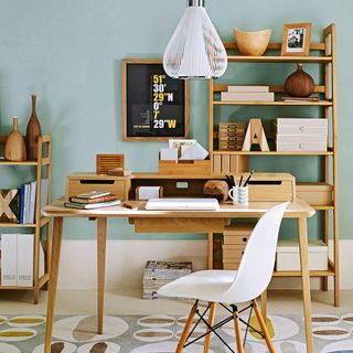 blue wall with wooden shelving unit desk and white chair