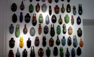 A wall display featuring 63 glazed porcelain vase beetles of varying colours and design.
