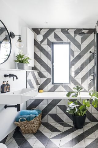 Bathroom with zig zag black and white tiles from floor up bath panel onto wall