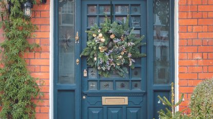 Navy front door with Christmas wreath and 27 sticker on window.
