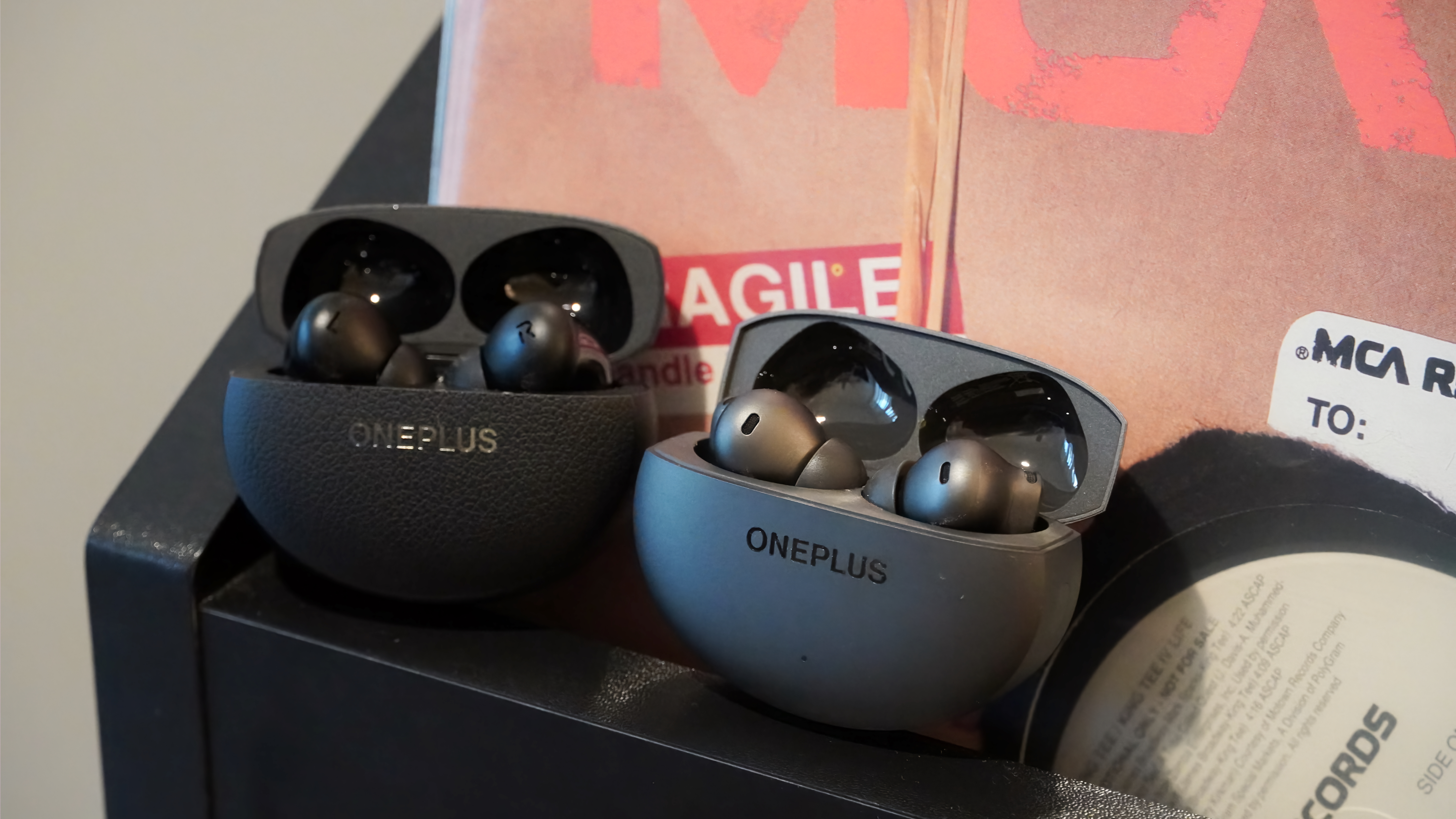 The OnePlus Buds 4 next to the OnePlus Buds Pro 3 on a record stand.
