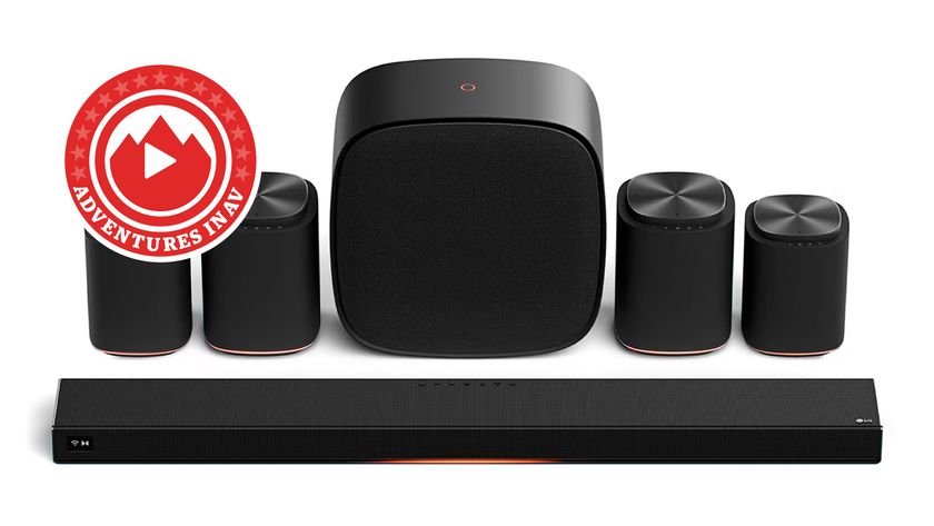 The full LG Sound Suite system (a soundbar, two pairs of wireless speakers and a wireless subwoofer) arranged against a white background. In the corner of the image is a red logo that says 'Adventures in AV'.