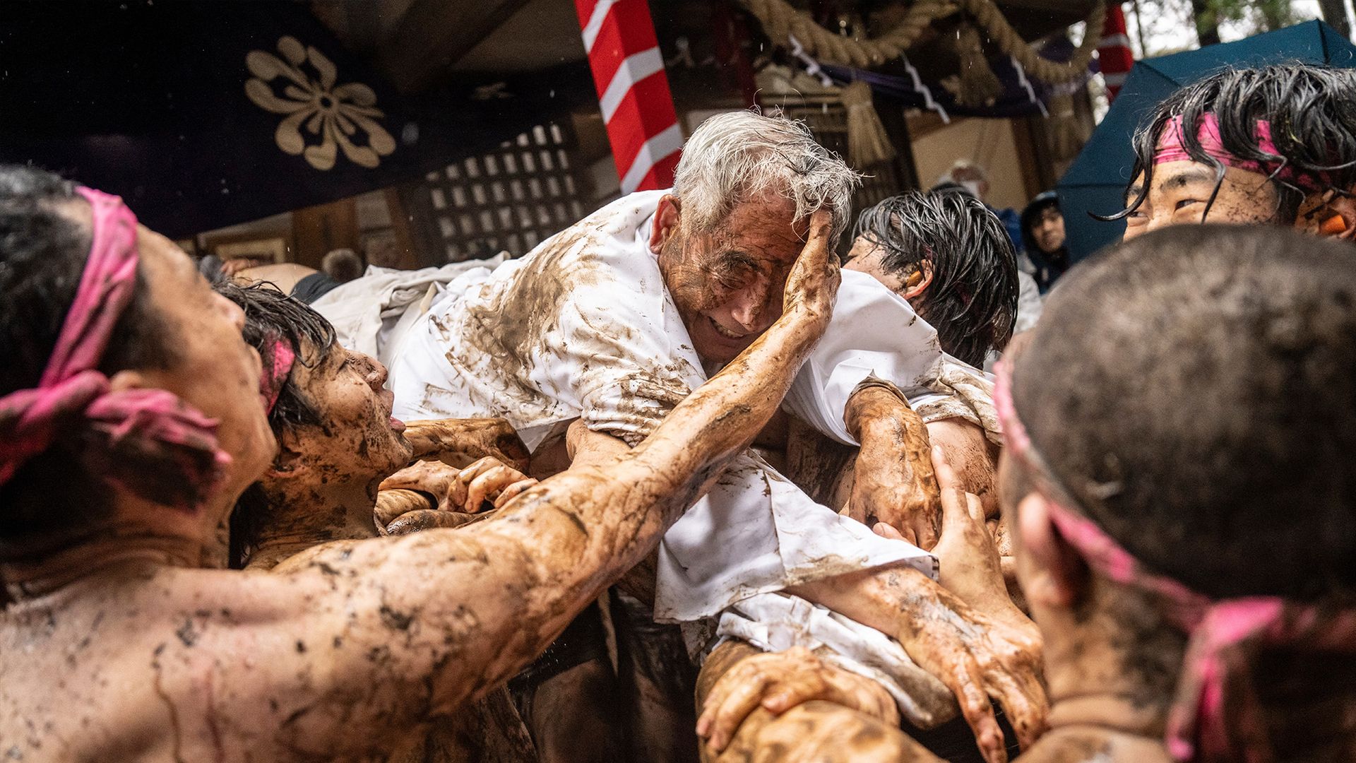 
                                Participants hold up a man and smear mud on his face during the Warabi Hadaka festival in Yotsukaido, Japan
                            