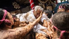 Participants hold up a man and smear mud on his face during the Warabi Hadaka festival in Yotsukaido, Japan